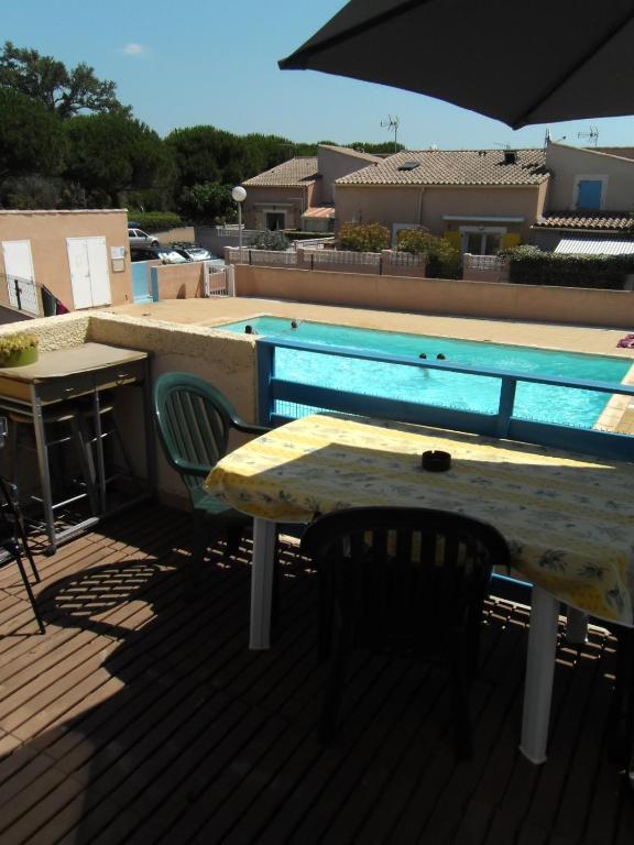 - une table et des chaises sur une terrasse avec piscine dans l'établissement Appartement en duplex à 400 m de la plage dans résidence avec piscine commune 1 chambre 4 couchages WIFI LXOND47, à Portiragnes