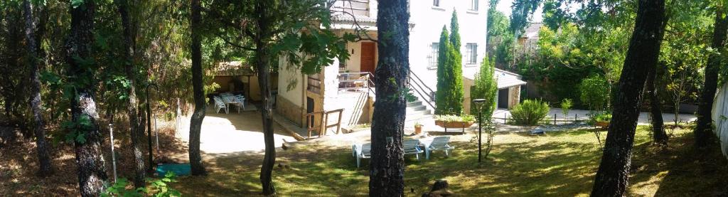 einen Garten mit Stühlen und ein Haus mit Bäumen in der Unterkunft El Rincón de Gredos in Navaluenga