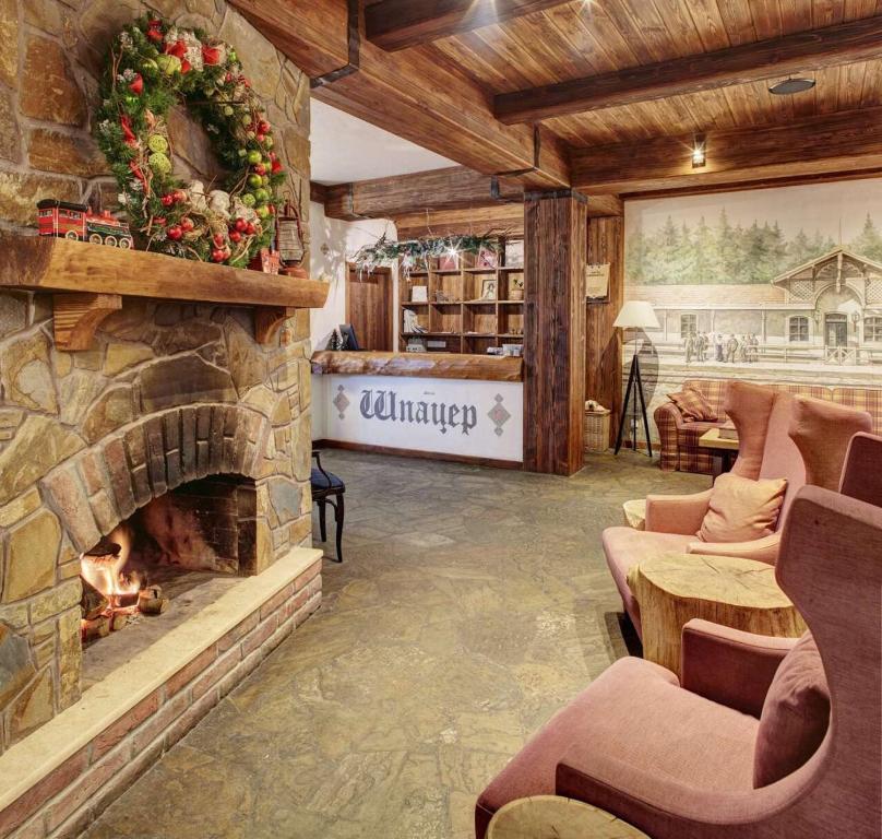 a living room with a stone fireplace in a lodge at Shpatser hotel in Briukhovychi