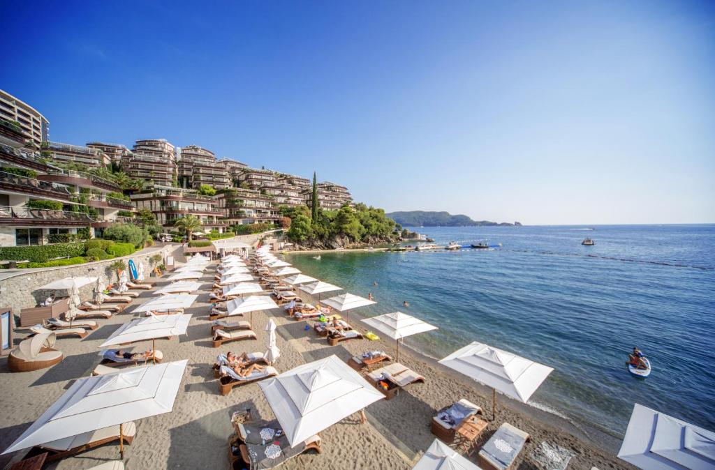 a beach with chairs and umbrellas and the water at Dukley Hotel & Resort in Budva