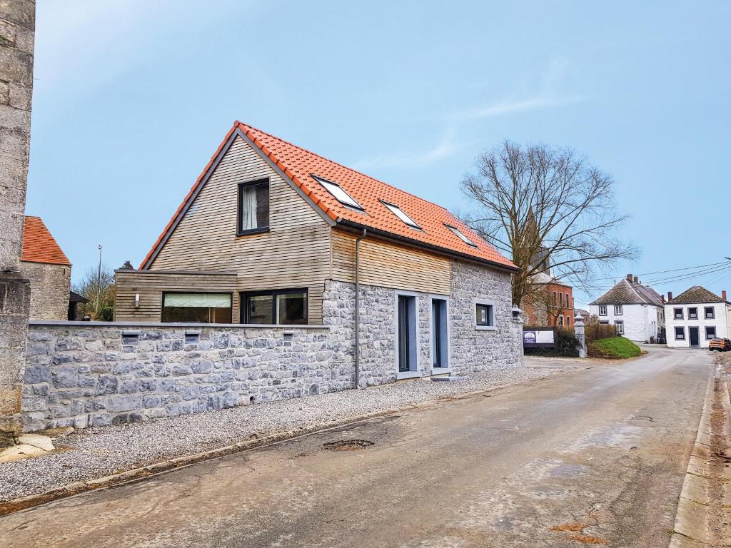 a stone house with an orange roof on a street at La petite maison dans la cour in Stave