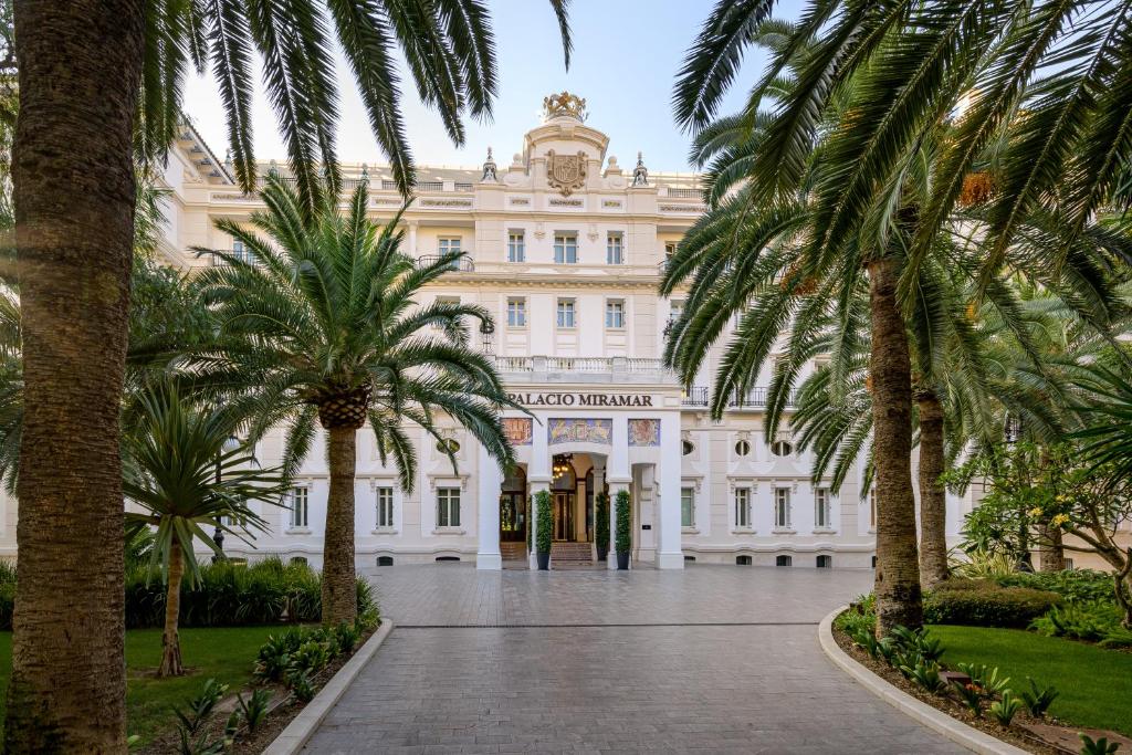 Un edificio con palmeras delante. en Gran Hotel Miramar GL, en Málaga