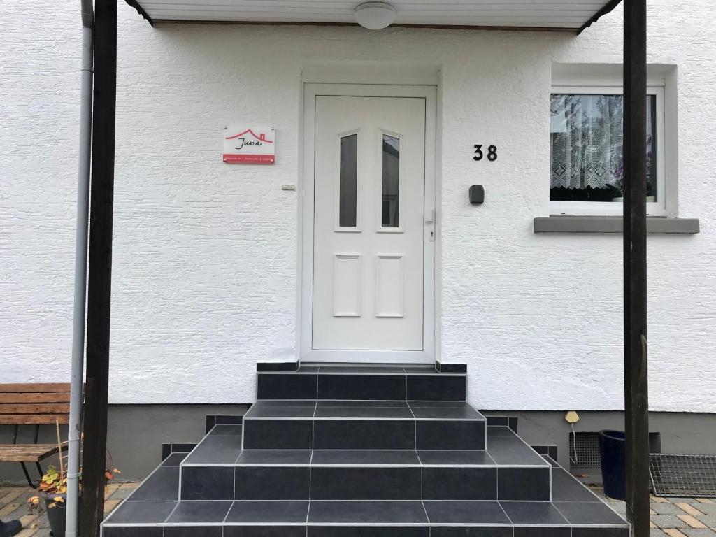 a white door on a white house with steps at JUNA in Karlsruhe