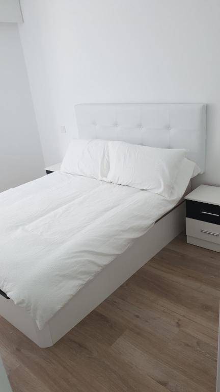 a bed with white sheets and a white wall at Apartamento estacion de esqui la pinilla in La Pinilla