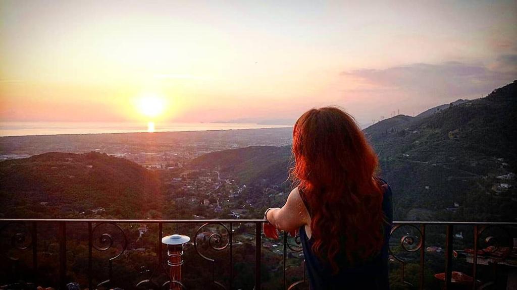 een vrouw op een balkon met uitzicht op de zonsondergang bij Dulcis in Borgo in Santa Lucia