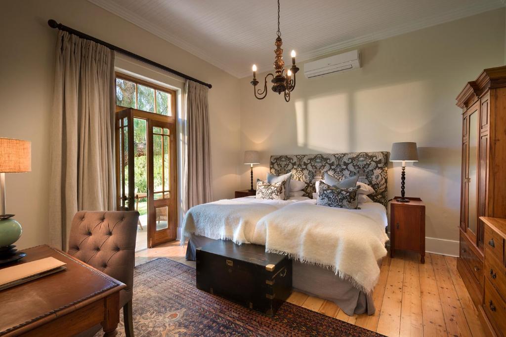 1 dormitorio con cama, escritorio y silla en Kwandwe Uplands Homestead, en Grahamstown