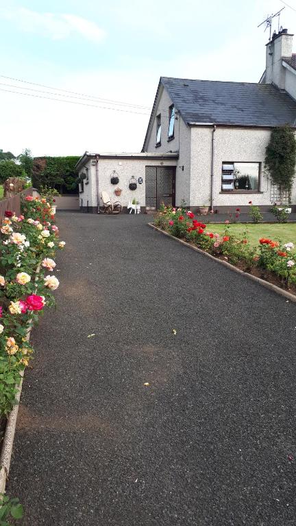 a house with a driveway with flowers in front of it at Bessies Cottage in Ahoghill