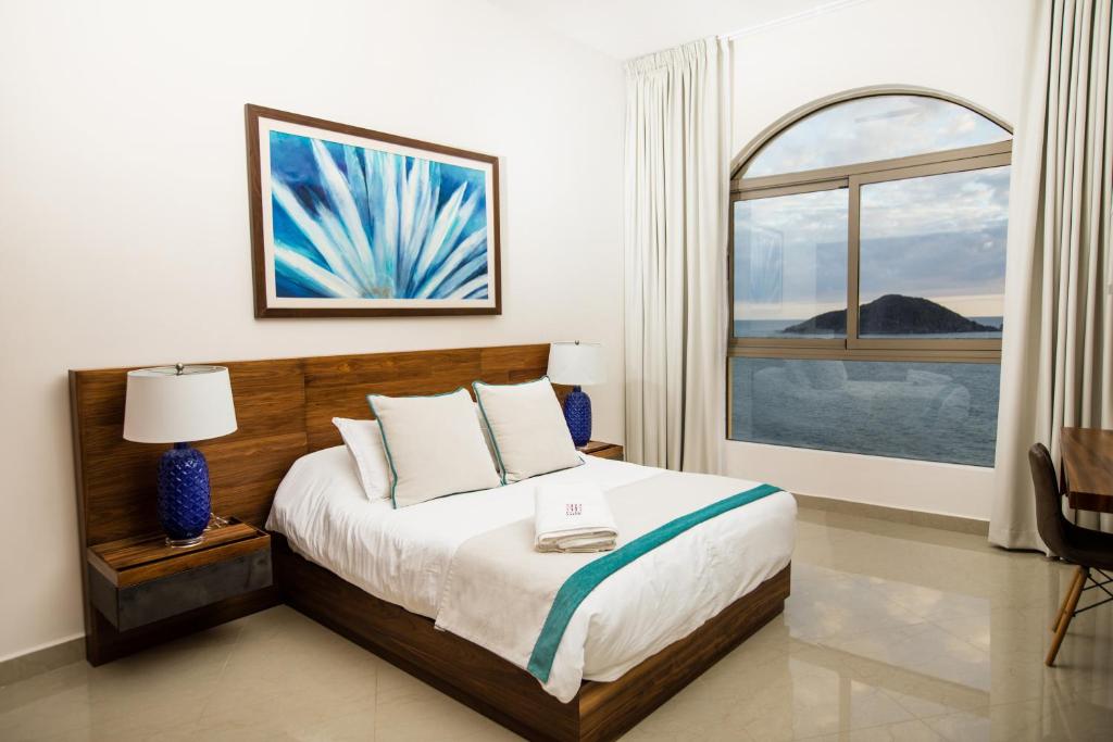 マサトランにあるPetit Luxe Las Gavias Penthouseのベッドルーム1室(ベッド1台、大きな窓付)
