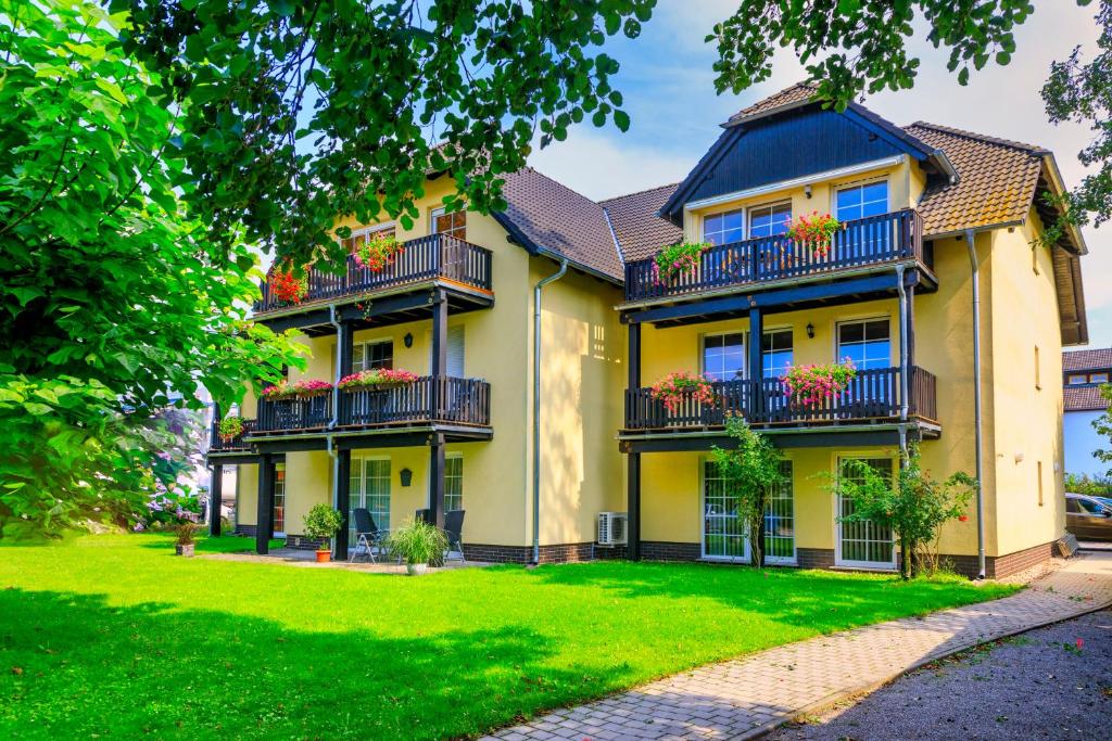 une grande maison jaune avec un balcon et une cour dans l'établissement Parkpension Spreewald, à Burg