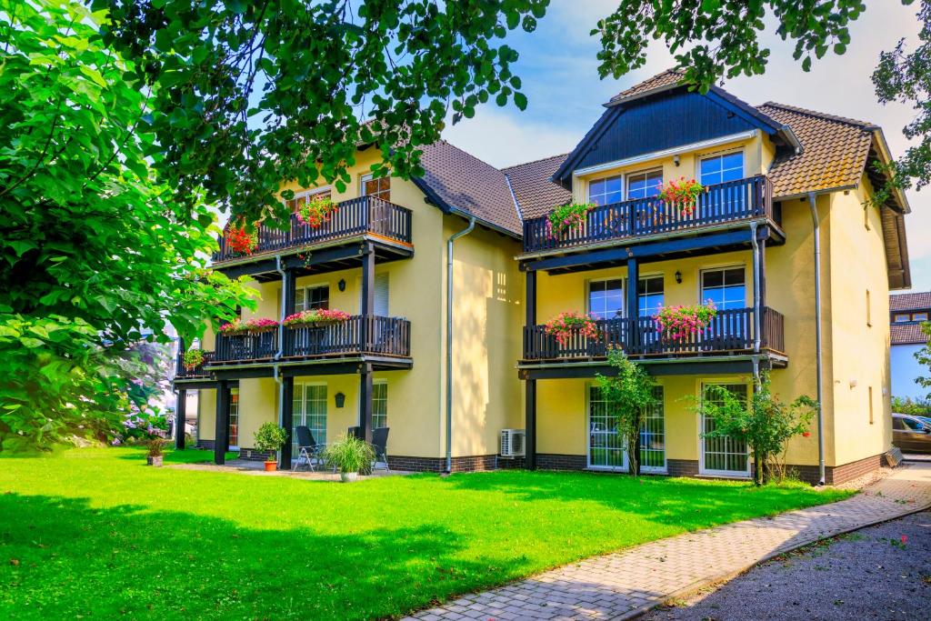 ein großes gelbes Haus mit Balkon und Hof in der Unterkunft Parkpension Spreewald in Burg