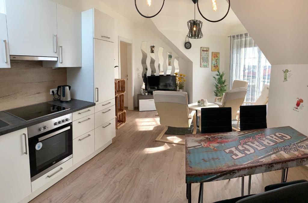 a kitchen with white cabinets and a table with chairs at Schöne und Helle Deutsch-Wagram Wohnungen in Deutsch-Wagram