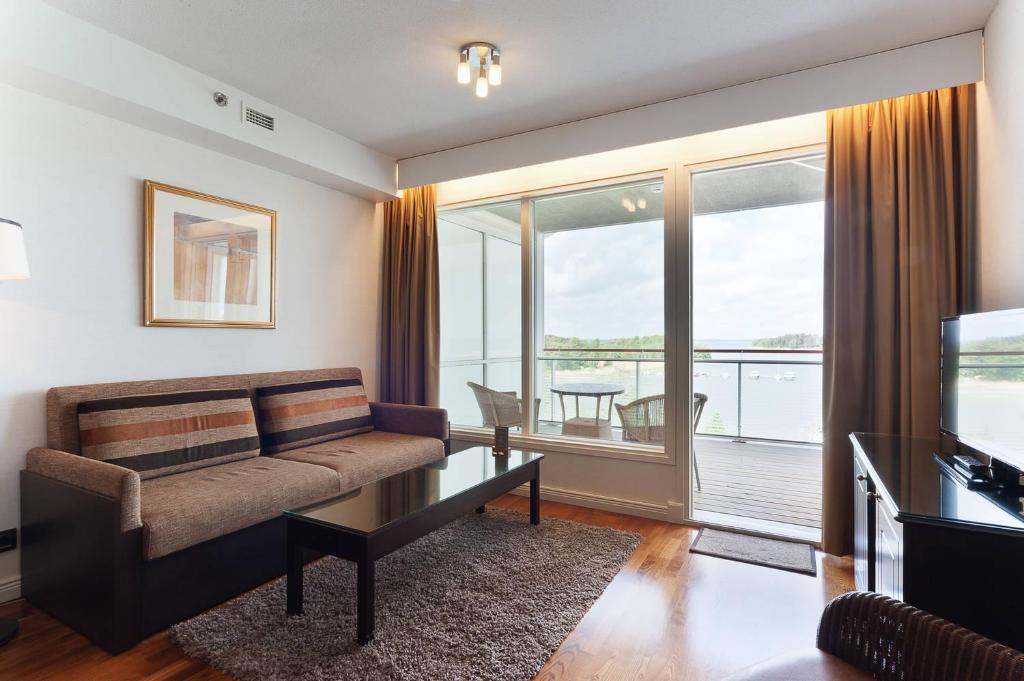 een woonkamer met een bank en een televisie bij Holiday Club Naantali Apartments in Naantali