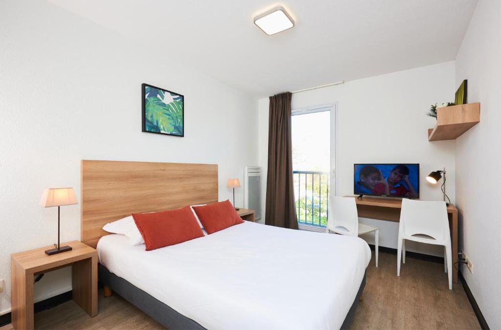 a hotel room with a bed and a desk and a bed at Ténéo Apparthotel Talence in Talence