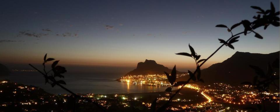 a view of a city and the ocean at night at Bayview Mountain Seafacing Cottages in Hout Bay