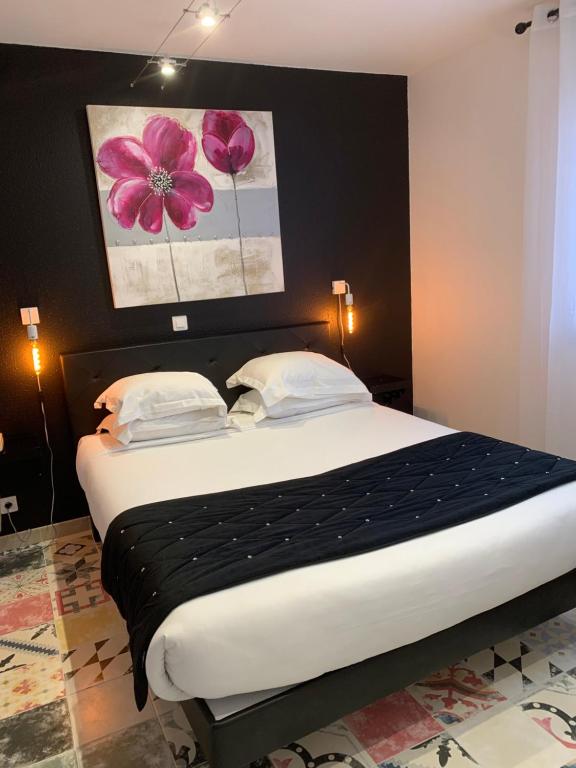 a bedroom with a large bed with a black headboard at Hotel Restaurant Baryton in Saint-Marcel