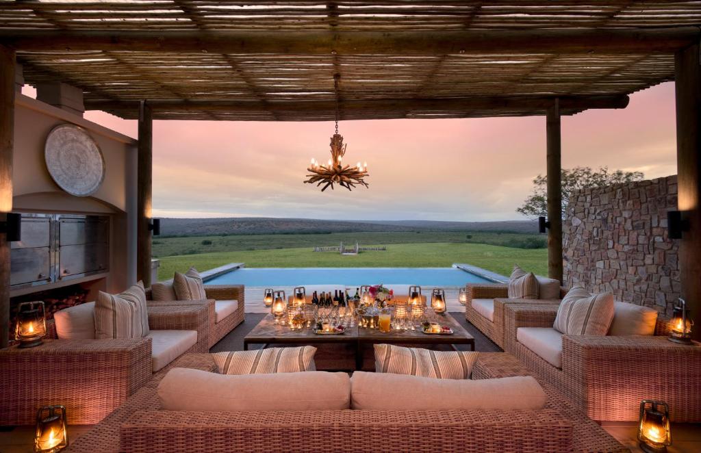 eine Außenterrasse mit Sofas, einem Tisch und einem Pool in der Unterkunft Kwandwe Fort House in Grahamstown