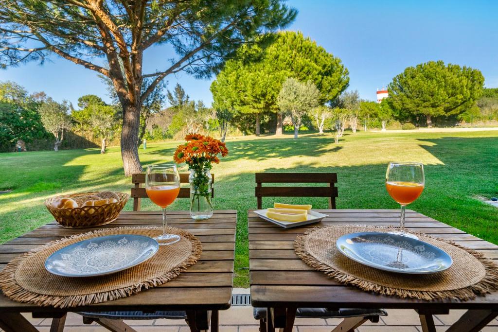 a wooden table with two plates and wine glasses at PARAISO DE ALVOR - A true paradise in an amazing nature place with direct access to the pool - Peace and relax - next to Alvor Village and the beach in Alvor