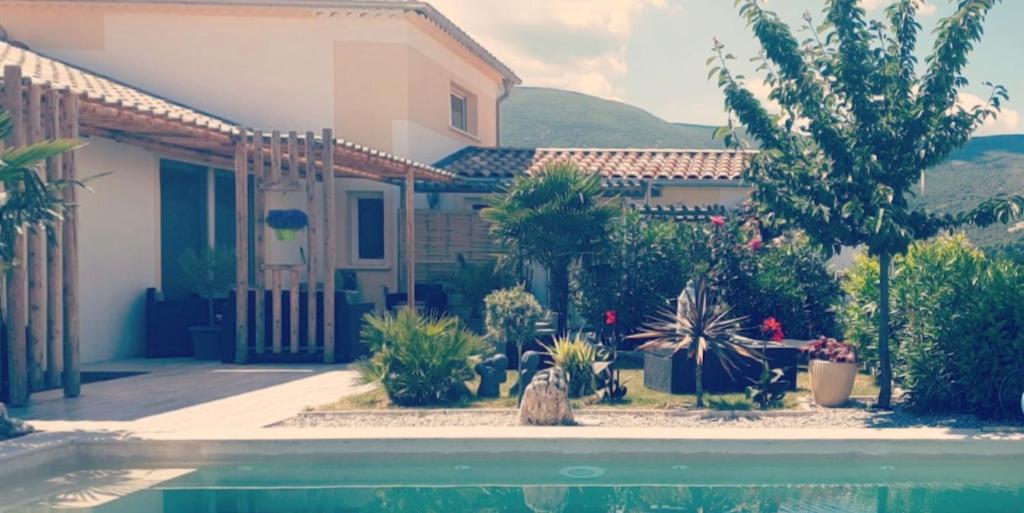 una casa con muchas plantas y una piscina en La Salamandre de l Olivier - le Palmier en Aubignosc