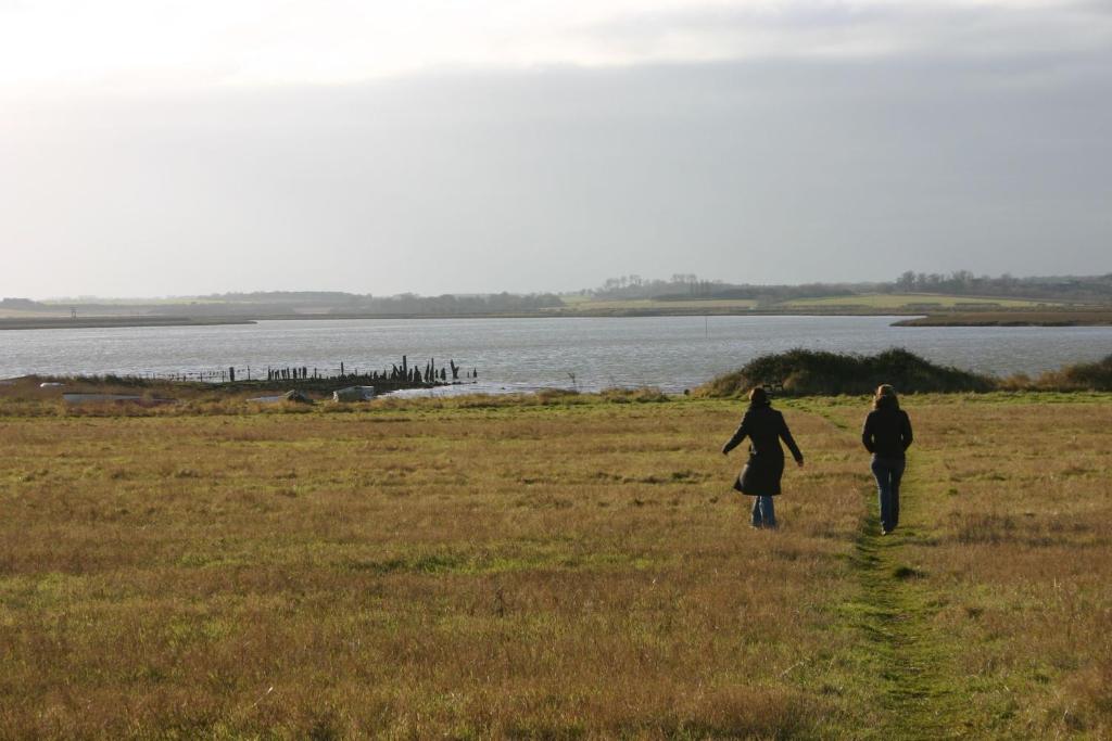 two people walking in a field near a body of water at Beaver Cottage in Aldeburgh