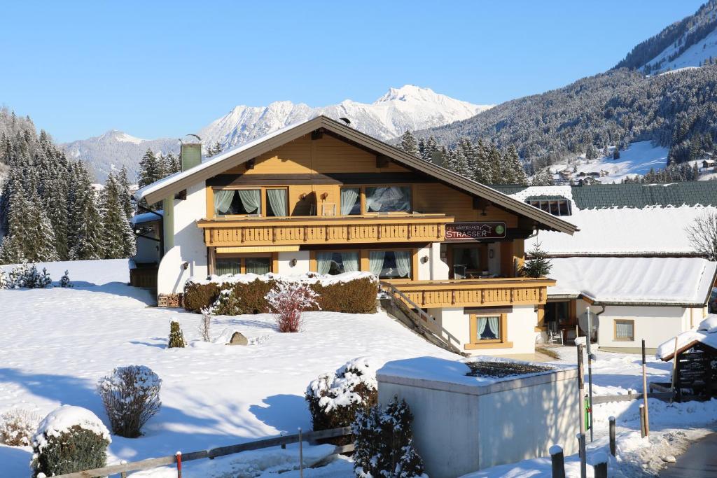 a house in the snow with mountains in the background at Gästehaus Strasser in Riezlern