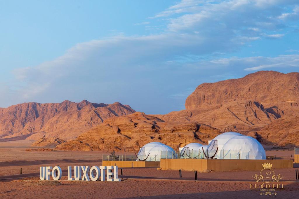duas cúpulas no deserto com montanhas ao fundo em Wadi Rum UFO Luxotel em Wadi Rum