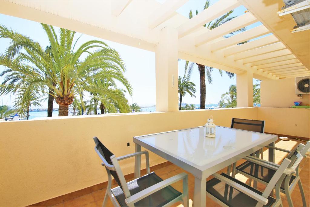 una sala da pranzo con tavolo, sedie e palme di Apartment MAKAI a Estepona