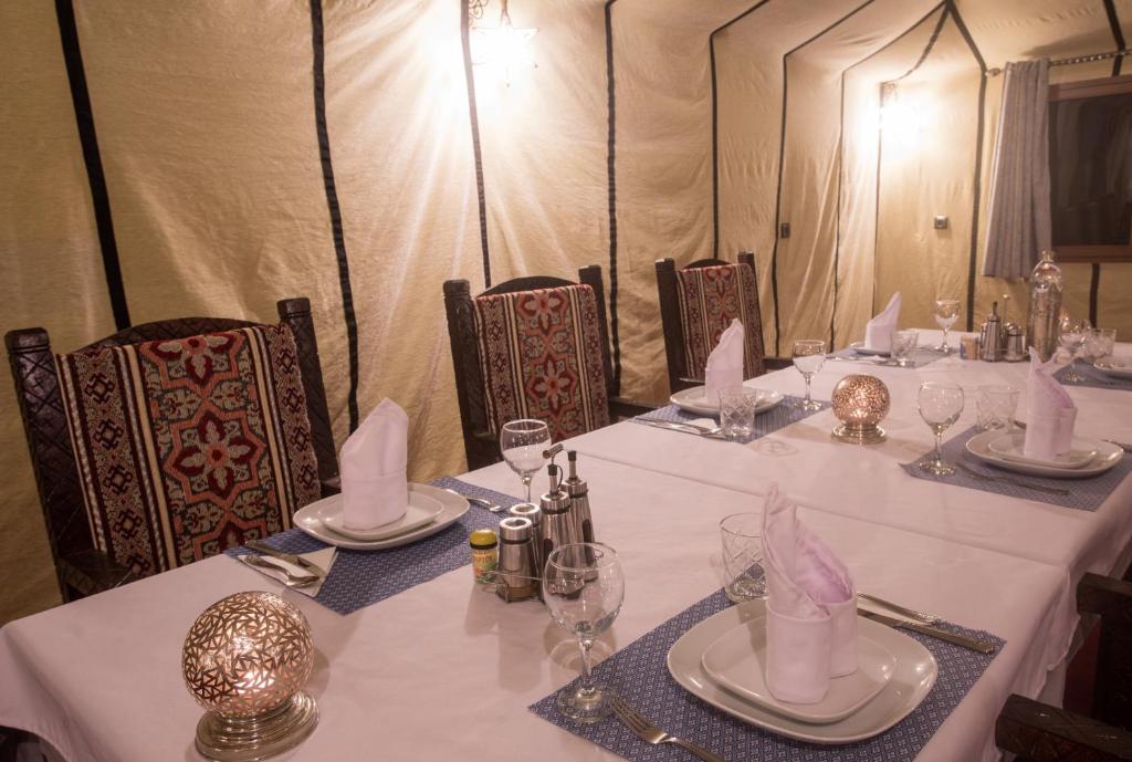 a table with white tablecloths and napkins on it at Luxury Desert Camp Amanar in Merzouga