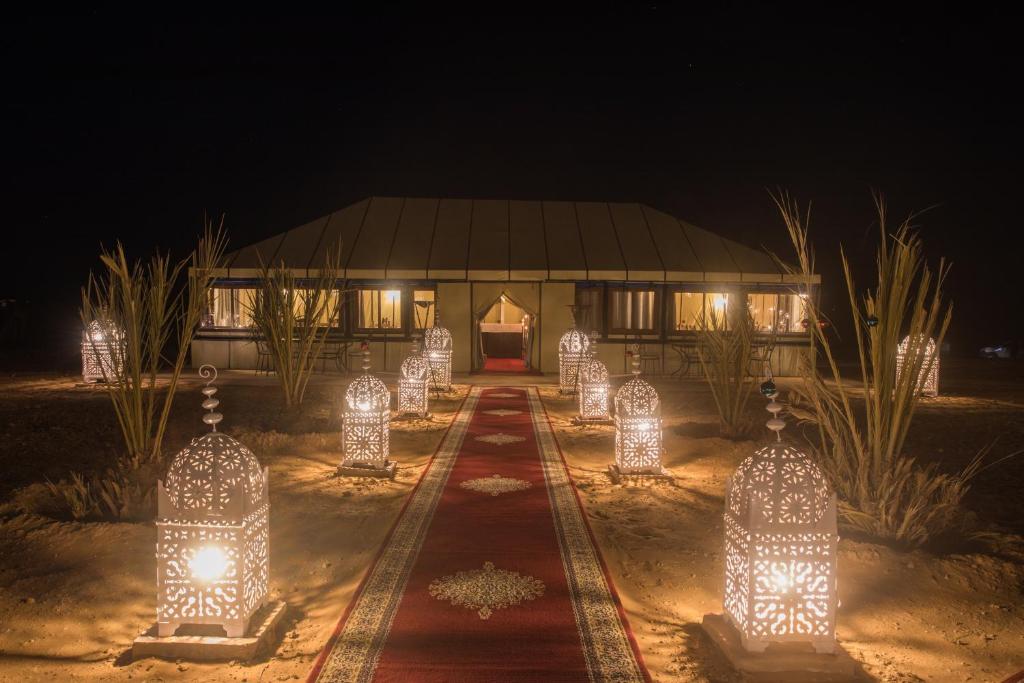 a building with lights in front of it at night at Luxury Desert Camp Amanar in Merzouga