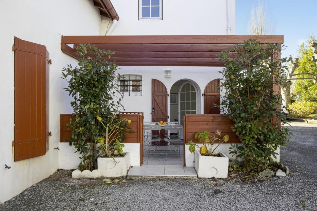Cette maison blanche dispose d'une terrasse avec deux plantes en pot. dans l'établissement Appartement Painel - 3 étoiles - Welkeys, à Biarritz