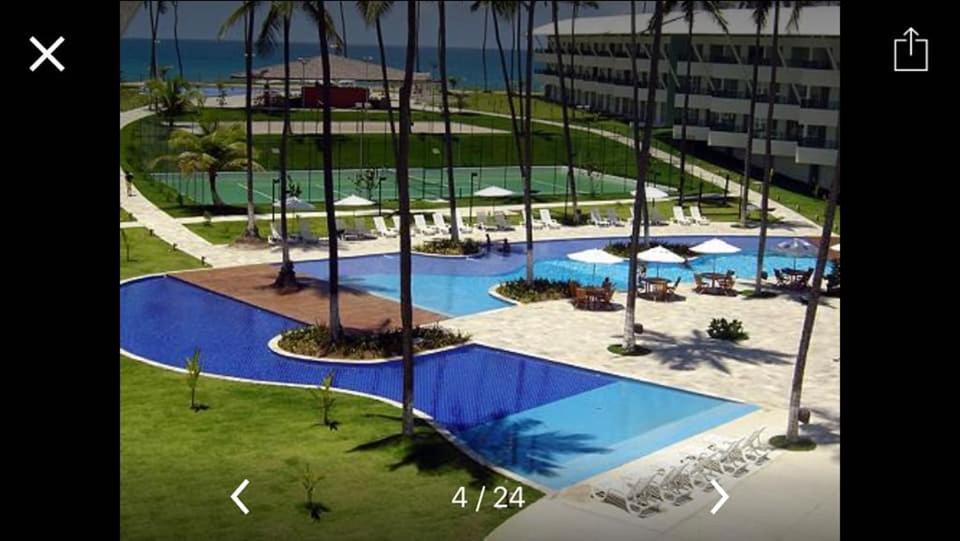 an aerial view of a swimming pool with chairs and umbrellas at Ancorar Flat Resort Porto de Galinhas in Porto De Galinhas