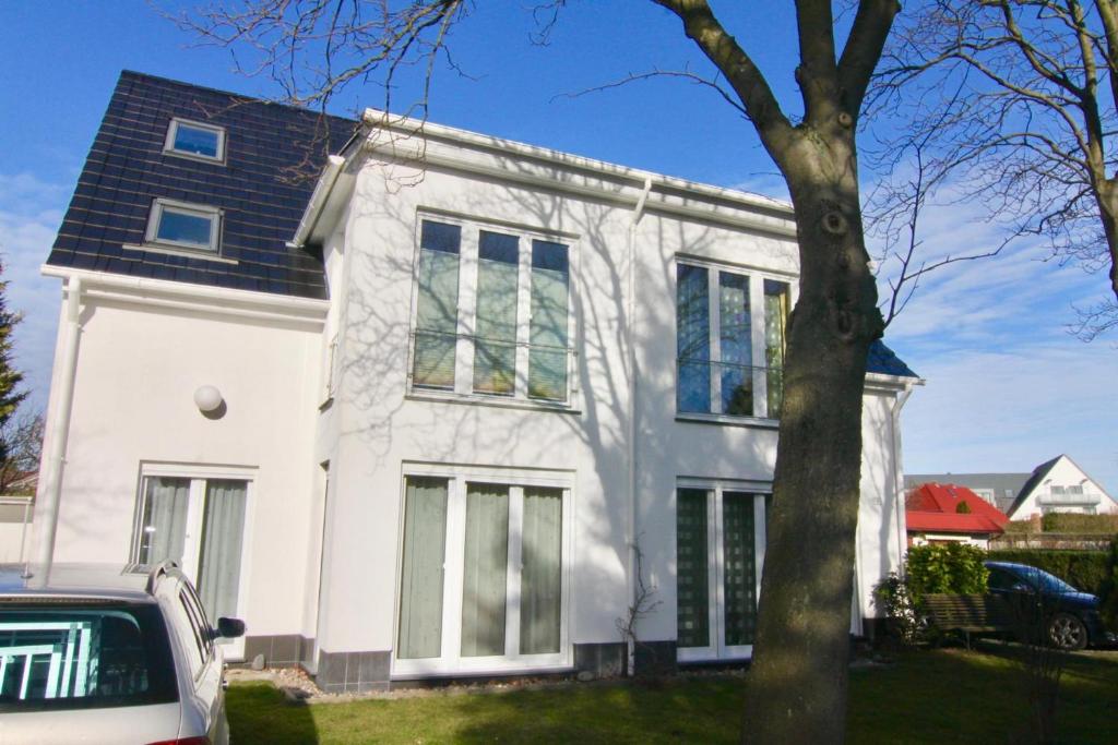een wit huis met een auto ervoor geparkeerd bij Haus Annelie FEWO 2 OG in Dranske