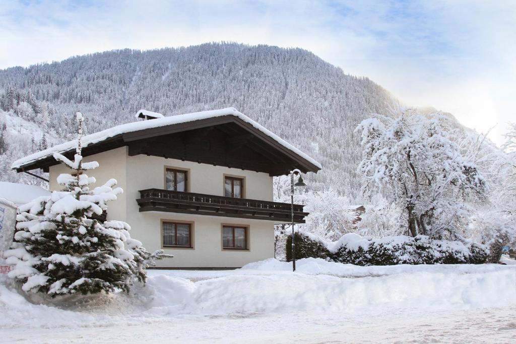 une maison recouverte de neige devant une montagne dans l'établissement #hostFLACHAU1, à Flachau