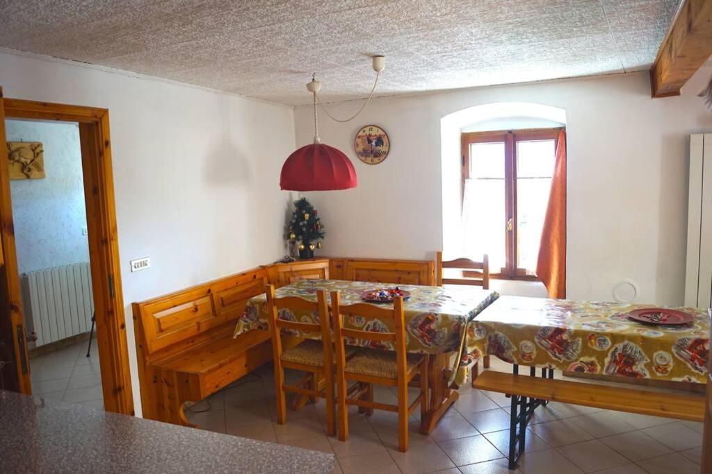 uma sala de jantar com uma mesa e cadeiras e uma janela em Casa rustica di montagna em Gignod