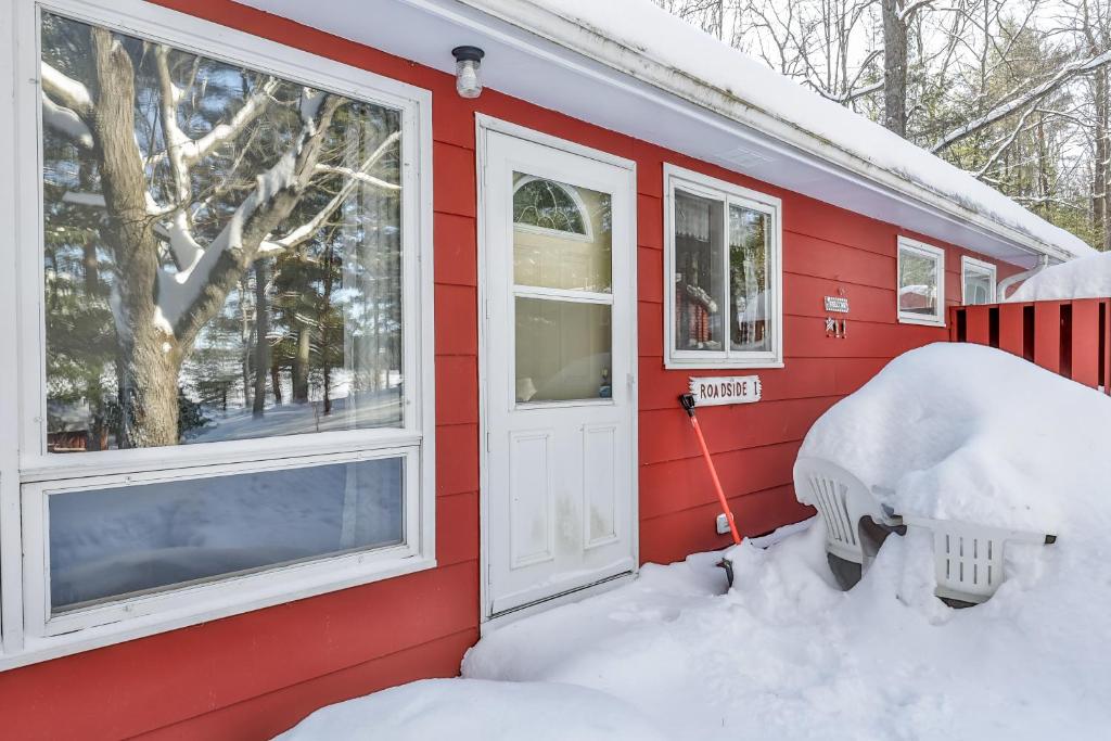 uma casa vermelha com neve à volta da porta e janelas em Roadside Duplex em Arbor Vitae