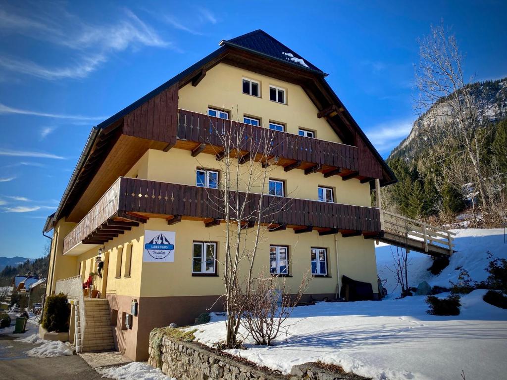 a large building with a wooden roof in the snow at Landhaus Tauplitz in Tauplitz
