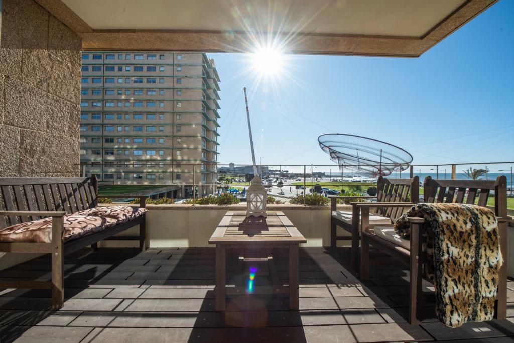 a balcony with benches and a table and a view of a building at Apartament em condominio com Piscina in Matosinhos