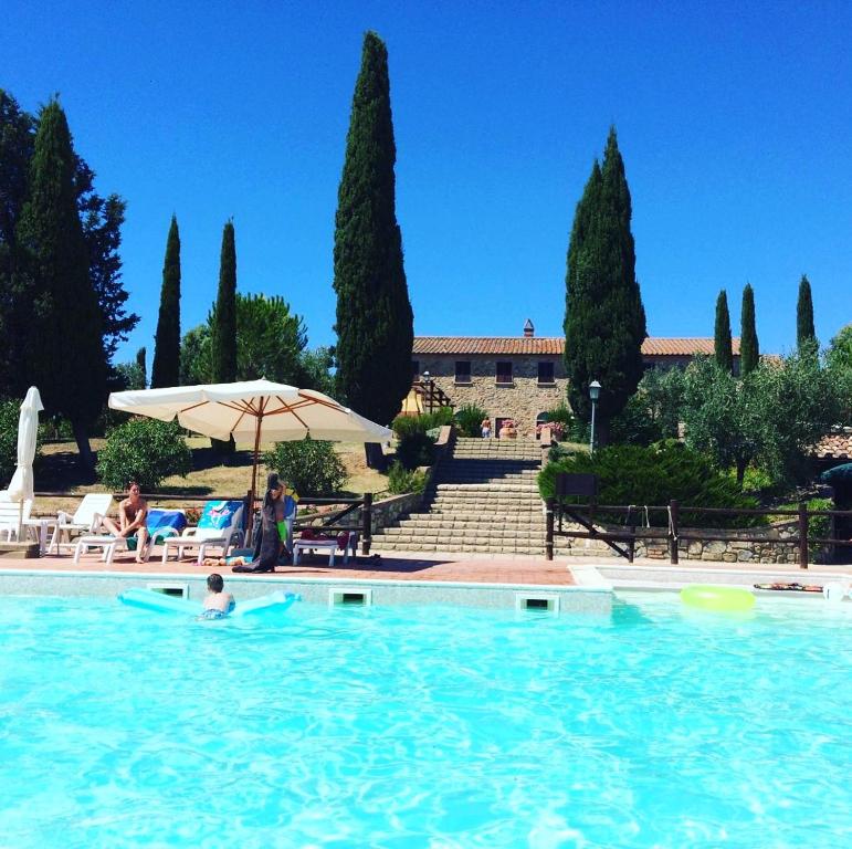 a person in a swimming pool with an umbrella at San Giorgio Country Residence in Santa Luce