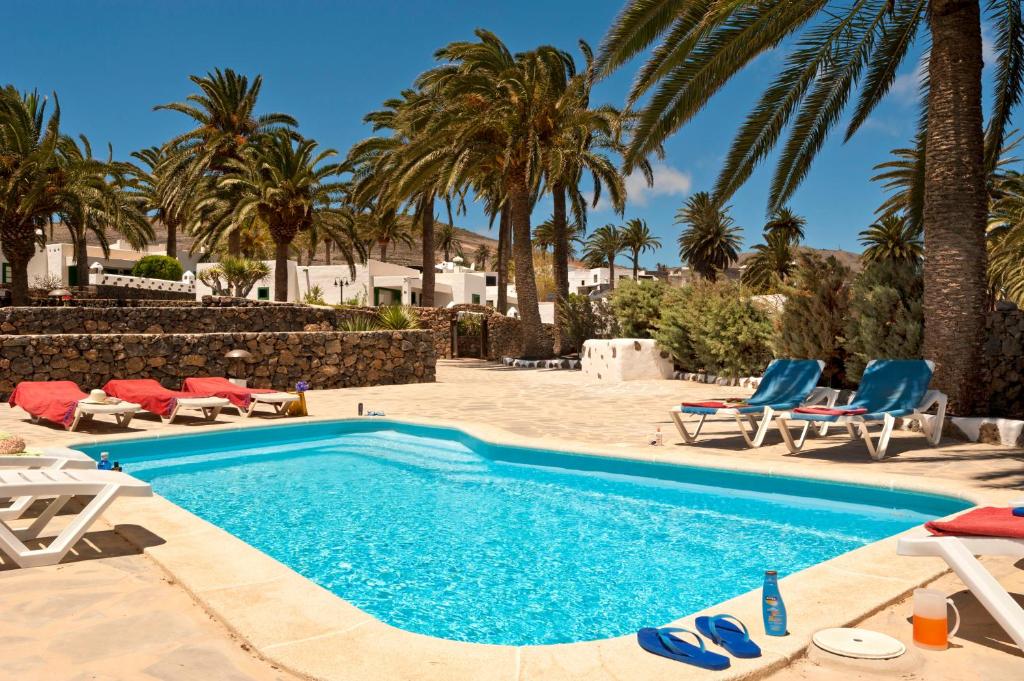 a swimming pool with chairs and palm trees at Finca la Crucita Haria Lanzarote By PVL in Haría