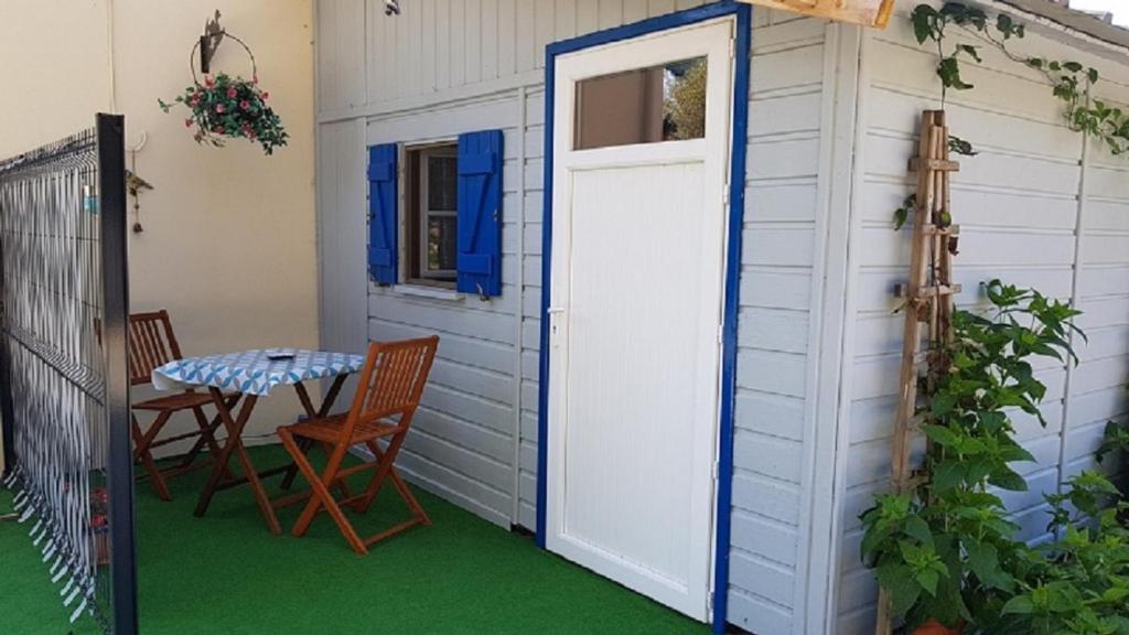 una puerta que conduce a un patio con mesa y sillas en Bungalow de Kermoal en Trébrivan