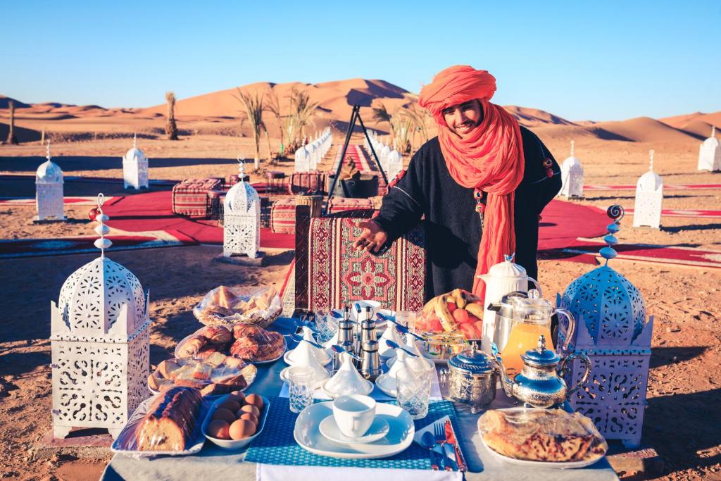 a woman standing in front of a table with food at Luxury Desert Camp Amanar in Merzouga