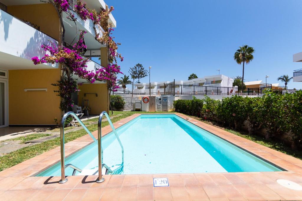 une piscine en face d'un bâtiment dans l'établissement Apartamentos Melusina en Playa del Inglés al lado de la playa y las Dunas de Maspalomas, à Playa del Ingles