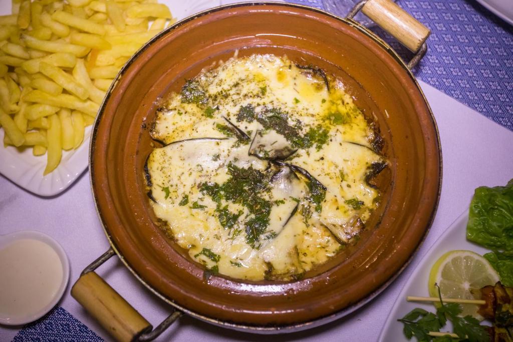 a bowl of food with cheese and herbs next to french fries at Luxury Desert Camp Amanar in Merzouga