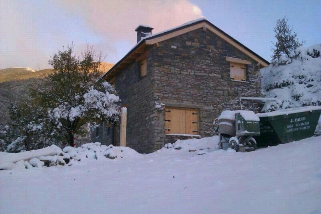 ein Steinhaus im Schnee mit einem Truck in der Unterkunft Casa Rural Pirineo Aragonés in Biescas