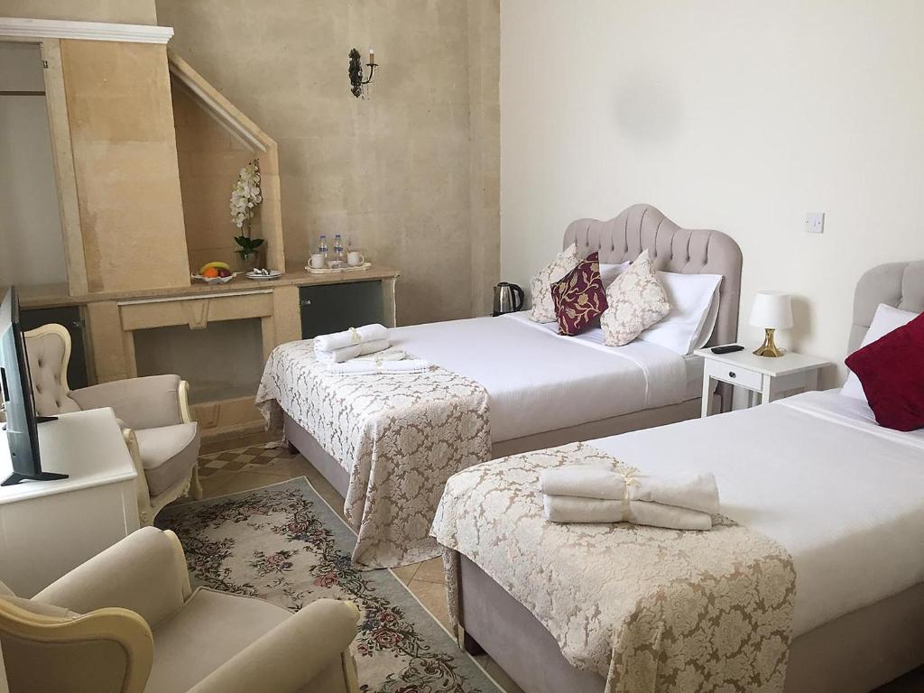 um quarto de hotel com duas camas e uma cadeira em Lord's Residence Boutique Hotel em Cirénia