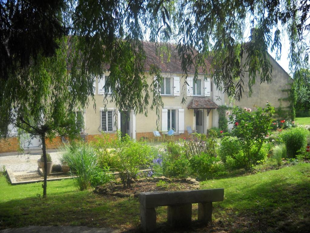 uma casa com um jardim e um banco em frente em RELAIS DES VIGNOTTES em Chevannes