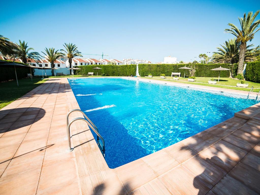 una piscina con agua azul y palmeras en Apartment Calas Blancas by Interhome en Torrevieja