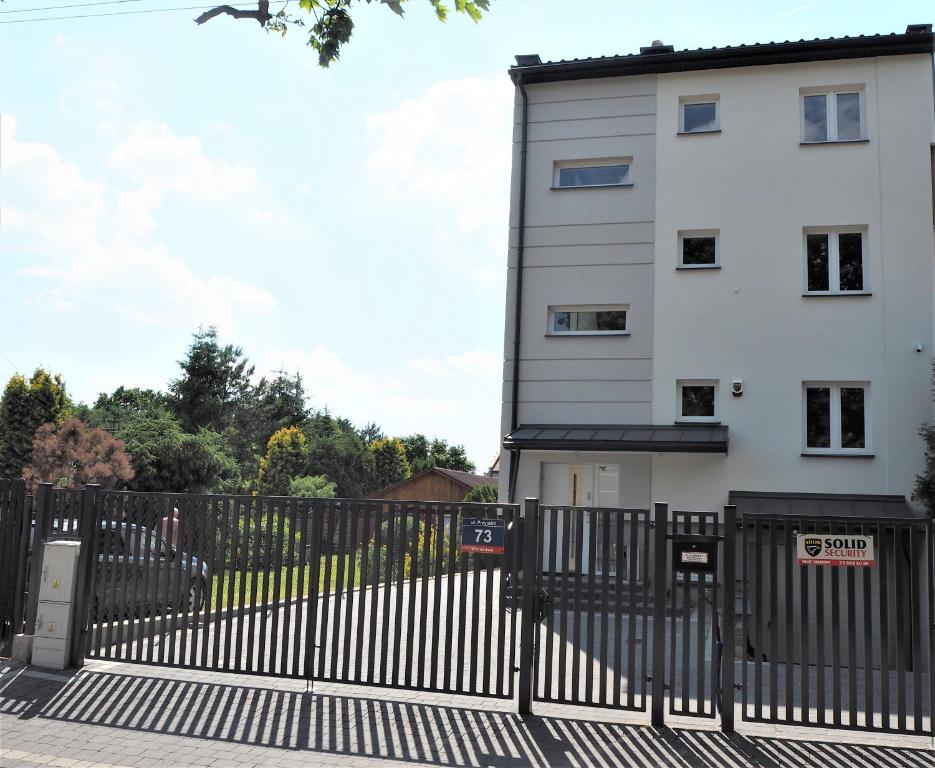 a white building with a black fence in front of it at Apartamenty Dobranoc - Wawer 2 in Warsaw