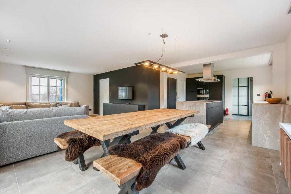 a kitchen and living room with a wooden table and benches at Big modern and bright villa near coast in Koksijde