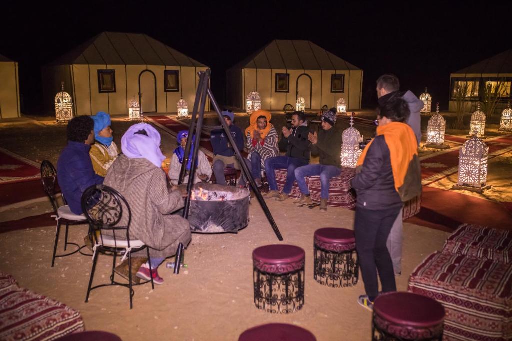 a group of people sitting around a table with a cake at Luxury Desert Camp Amanar in Merzouga