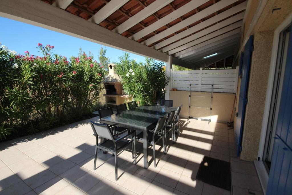 une table et des chaises assises sur une terrasse dans l'établissement Belle villa climatisée, wifi, 3 chambres grande terrasse vue réserve naturelle dans résidence sécurisée avec piscine commune 800m de la mer Un vrai Havre de Paix LRCS107, à Portiragnes